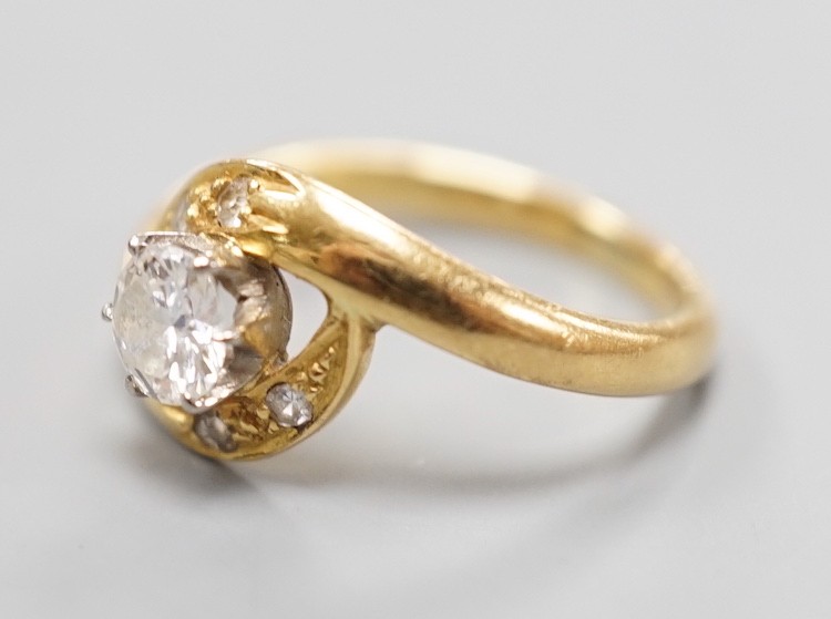 A continental yellow metal and single stone diamond set ring, with diamond set crossover shoulders, size I, gross weight 3.2 grams.
